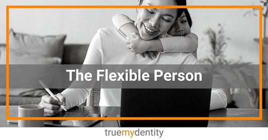 Mom is flexible person working on laptop trying to take notes on tablet while on video chat with childs arms around moms neck True Mydentity