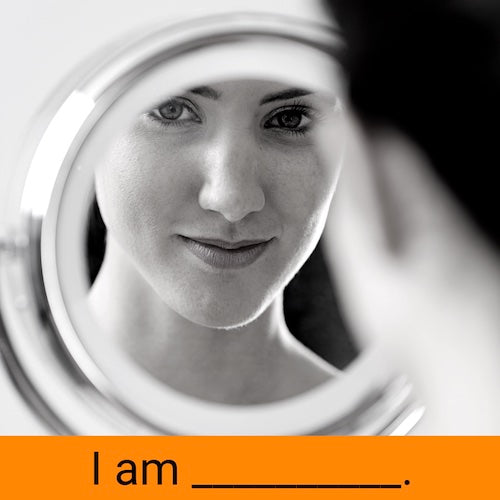 young woman holding and looking into mirror smiling discovering self character traits powers