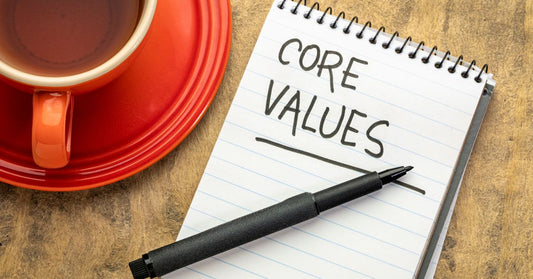 notepad with black marker and cup of tea sitting on table with core values written to begin looking at personal value list