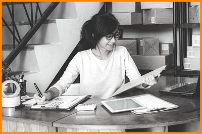 disciplined young woman managing business checking purchase orders on clipboard