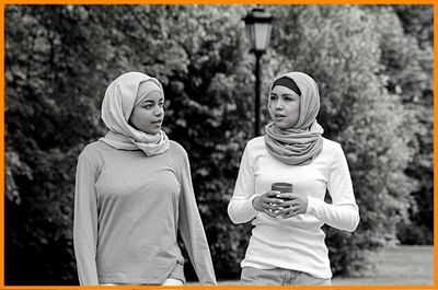 two young women walking in park enthusiastically reflecting having important conversation